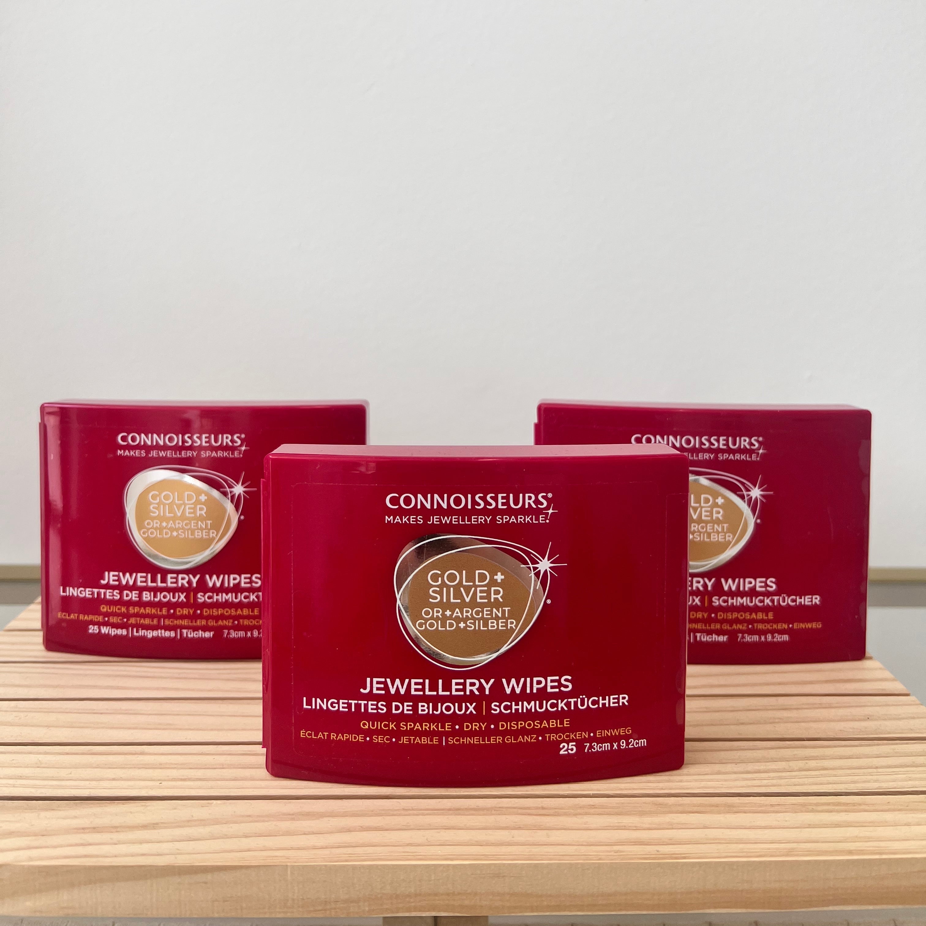 Three boxes of Connoisseurs Gold & Silver Jewellery Wipes on a wooden surface with a white background.