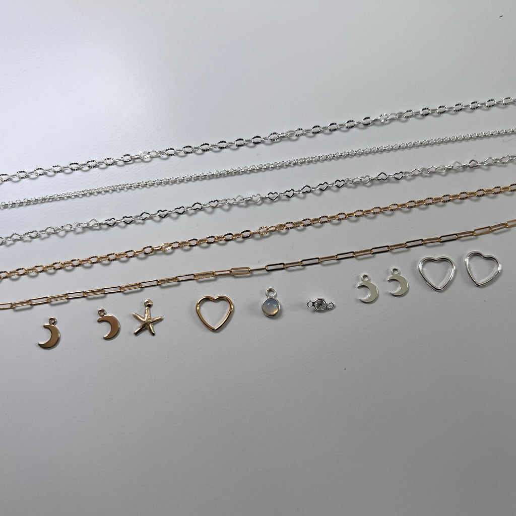 Set of silver necklaces with various pendants on a light gray background