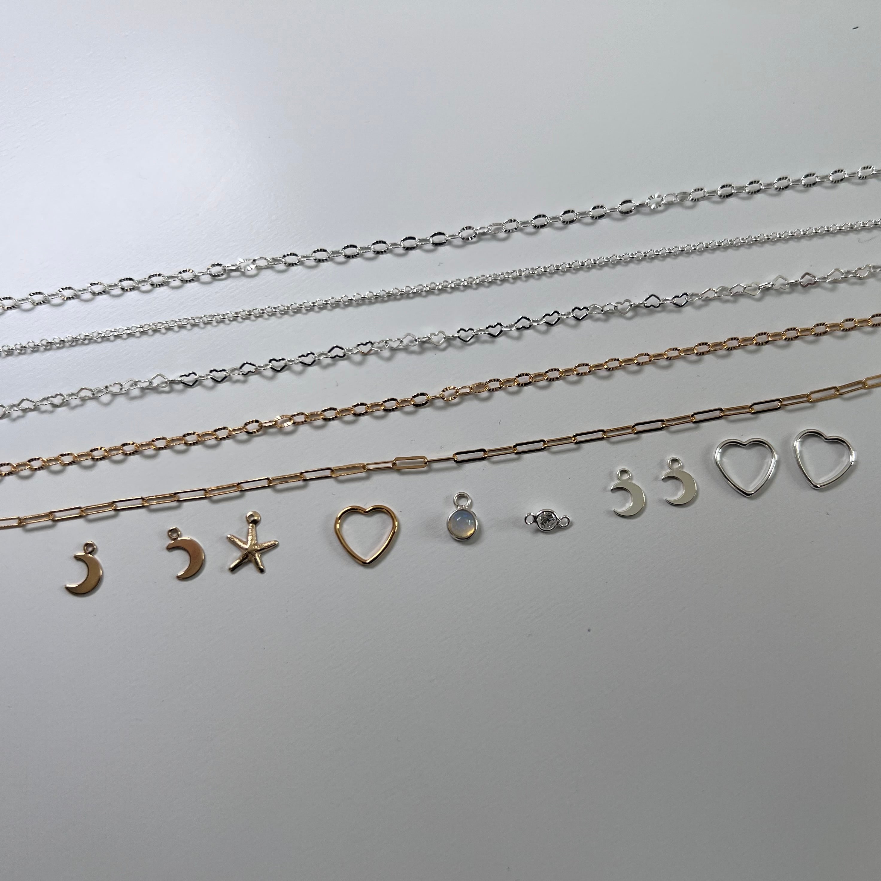 Set of silver necklaces with various pendants on a light gray background