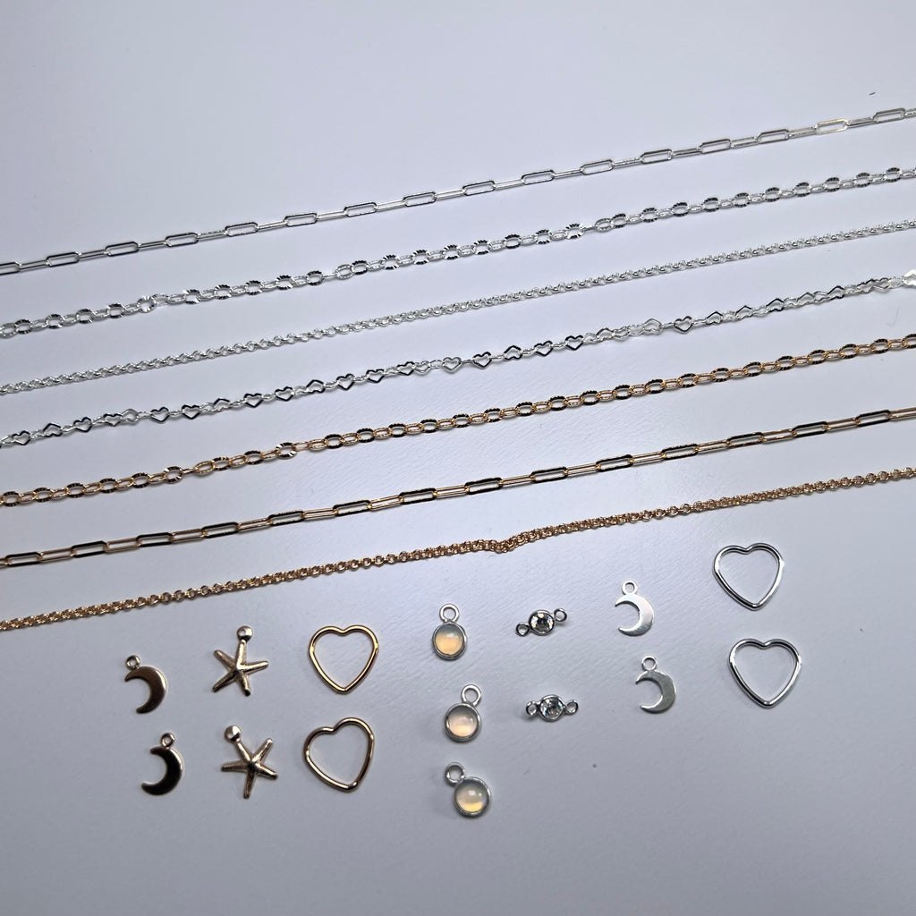 Collection of silver necklaces and charms on a light gray background