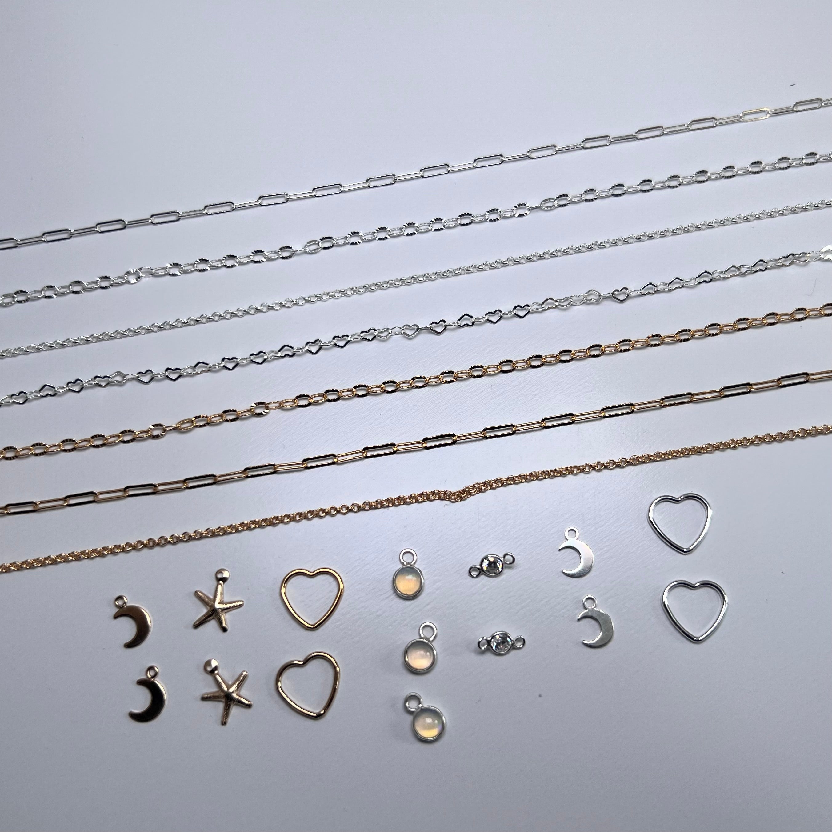 Collection of silver necklaces and charms on a light gray background